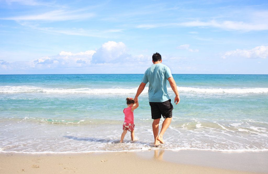 A Parent's Blessing. A father holds a daughter's hand while walking on the beach.