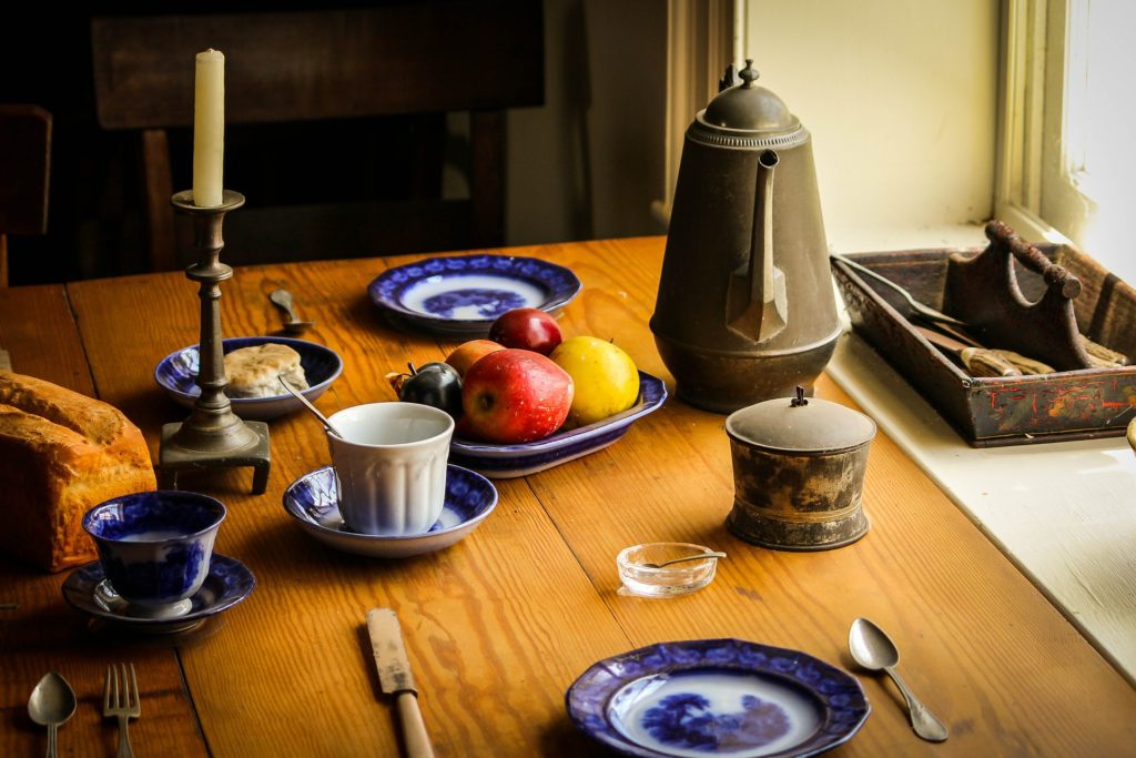 Hospitality: A Call to Open Hearts and Homes_still life of farmhouse table with two blue place settings, coffee cups, fruit, pitcher