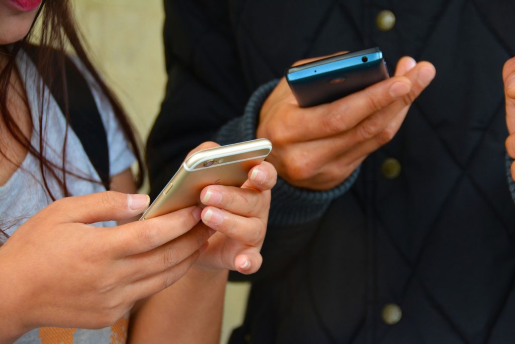 Hearing God's Voice in the Ordinary_hands of female and male holding smartphones, texting