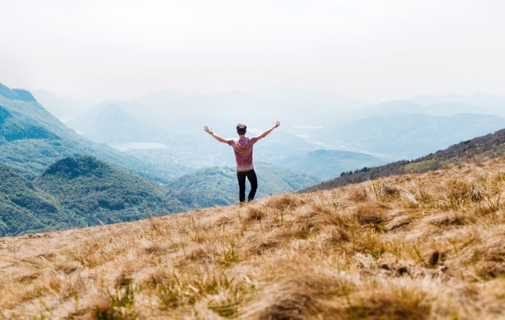 What to Do When You Don't Get What You Want_man standing on hillside overlooking mountains, hands lifted high