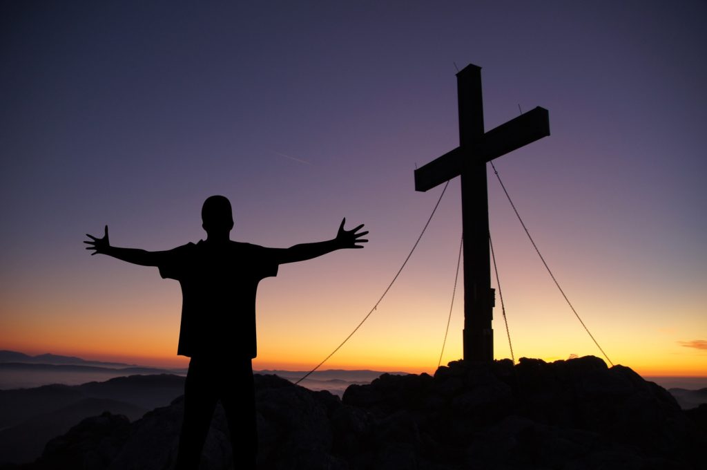 When Your Worst Day Becomes the Best Gift Ever_Man with arms outstretched standing in front of a cross, all in silhouette