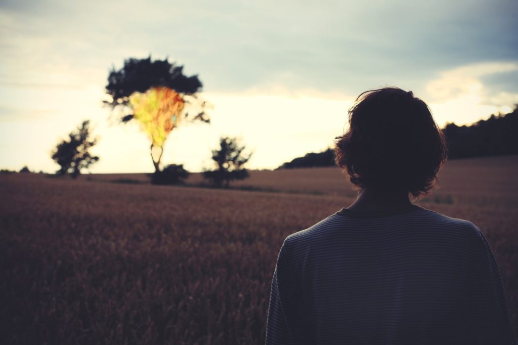 Young man in foreground, looking at burning tree in background