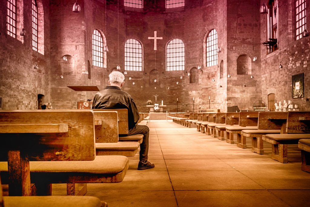 The Best Thing About Surrendering to God's Will_rear view of older man sitting in a stone church